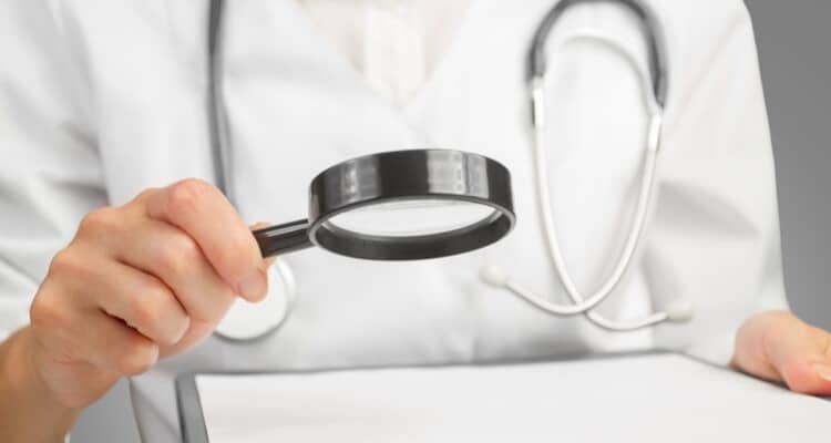 a nurse researcher looking at a magnifying glass