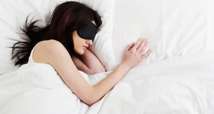 a nurse sleeping in bed wearing an eye mask