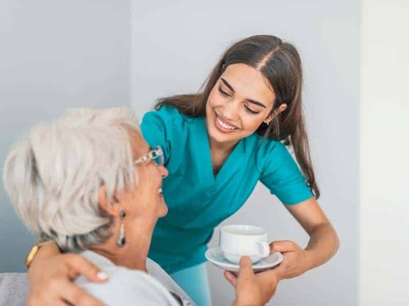 nurse aide bringing coffee to patient