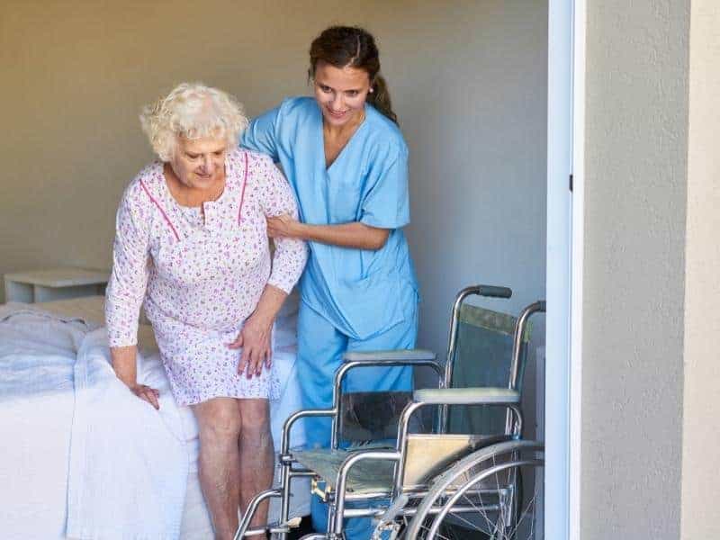 nurse aide helping elderly patient transport