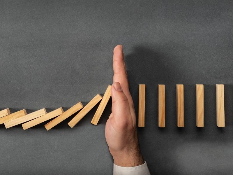 hand stopping the falling domino blocks