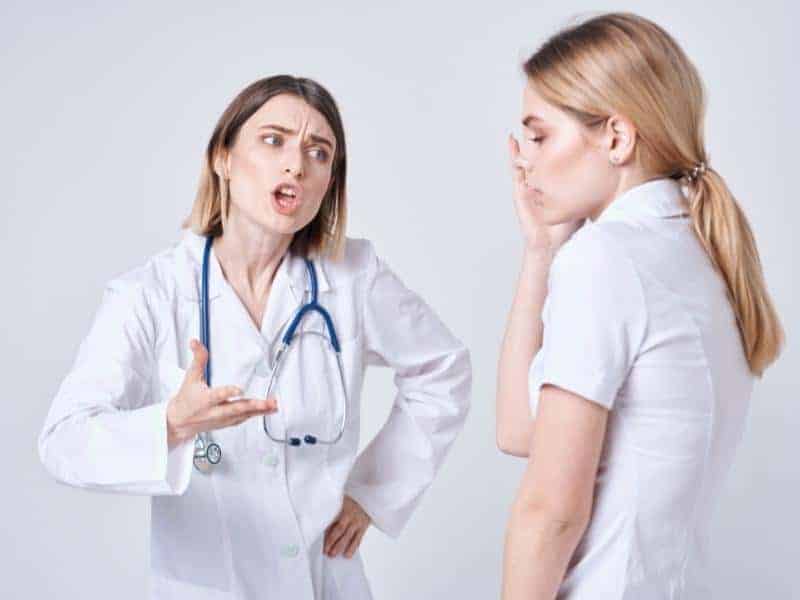 nurse arguing with a nurse holding her face