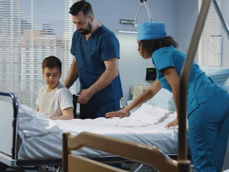 a nurse with one eye lifting patient into his bed