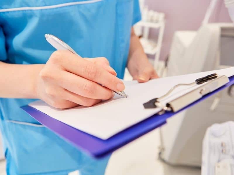 nurse writing in clipboard